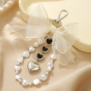 Détail du porte-clés à nœud en dentelle avec pendentifs cœurs et perles sur satin