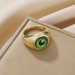 Makro-Detail eines goldenen Augenrings mit realistischem grünem Augapfel auf Schmuckschatulle