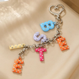 Détail de breloques alphabet colorées en strass avec fermoir cœur sur tissu en soie