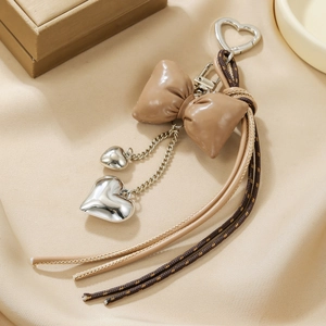 Detail of leather cherry bow and silver heart charms on a stylish bag accessory