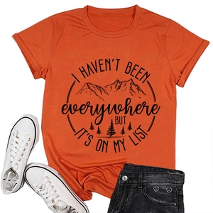 Flachbild eines orangefarbenen T-Shirts mit Bergmotiv und Schuhen für den Sommerurlaub