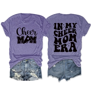 Flat lay of purple Cheer Mom Era t-shirt featuring vintage print and denim shorts