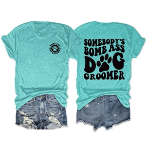 Flat lay of dog groomer graphic tee in teal with denim shorts on white background