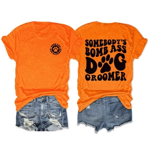 Detail view of orange dog groomer t-shirt and ripped denim shorts laid flat on white background