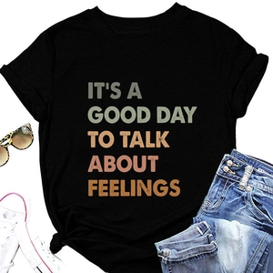 Flat lay of black cotton T-shirt with vintage slogan print and summer casual accessories