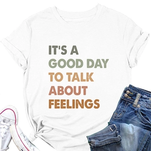 Detailed flat lay of white cotton T-shirt with colorful motivational text and denim styling