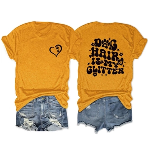 Flat lay detail of mustard yellow t-shirt with dog hair is my glitter print and denim shorts