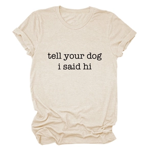 Close-up of oatmeal t-shirt featuring tell your dog i said hi slogan and fabric texture
