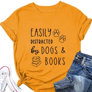 Flat lay of an orange T-shirt featuring dogs and books print with denim and shoes