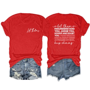 Détail d'un t-shirt rouge avec citation au dos et d'un short en jean bleu délavé et déchiré