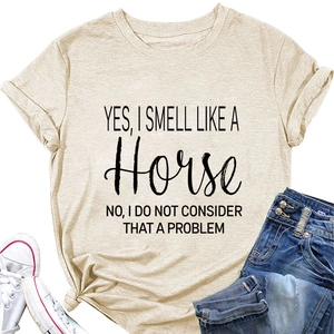 Beige T-shirt met paarden-slogan naast blauwe jeans en witte canvas schoenen plat gelegd