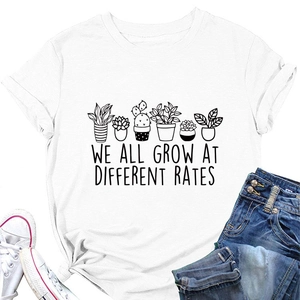 Flat lay of white T-shirt with plant print and 'WE ALL GROW AT DIFFERENT RATES' quote