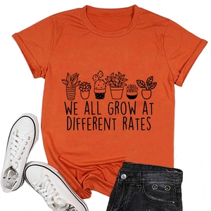 Flat lay of orange T-shirt with succulent print and 'we all grow at different rates' text