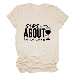 Détail du t-shirt couleur avoine avec slogan sips about to go down et verre de vin