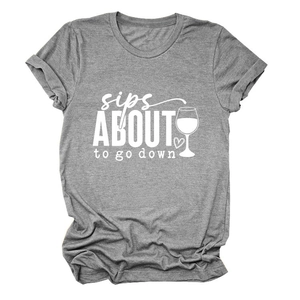 Détail du texte sips about to go down et du motif verre de vin sur le t-shirt gris