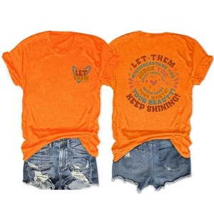 Detail of orange T-shirt with 'Let Them Misunderstand You' text and denim shorts