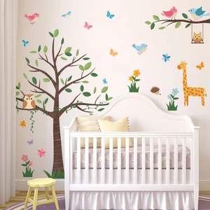 Detail of cartoon giraffe and tree wall decals in a cozy nursery with a white crib