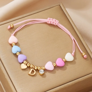 Macro detail of handmade pink beaded bracelet with heart charms and crystal letter D pendant