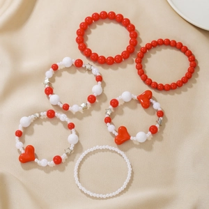 Detailansicht von 6-teiligem Set aus roten und weißen Perlenarmbändern mit Herzanhängern