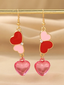 Detail of pink resin heart earrings with gold hooks and sparkling crystal accents