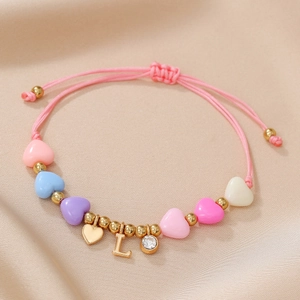 Close-up of pink beaded bracelet with heart charms, gold letter L and crystal pendant