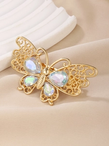Macro shot of golden butterfly hair clip with hollow details and iridescent gems