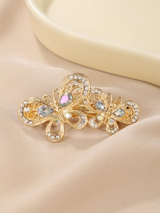 Detailed close-up of a golden double butterfly hair clip with rhinestones and crystals