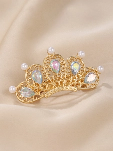 Detailed view of crown hair clip with gold filigree, white pearls and colorful rhinestones