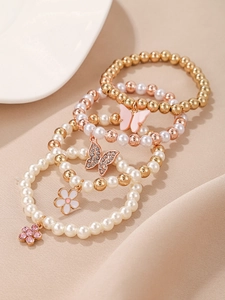 Détail de quatre bracelets en perles avec pendentifs papillon et fleurs en or et rose