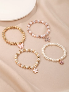 Détail de quatre bracelets en perles avec breloques papillon rose et fleurs émaillées