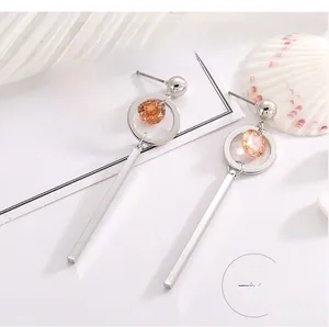 Detail view of silver drop earrings with champagne zircons on white fabric