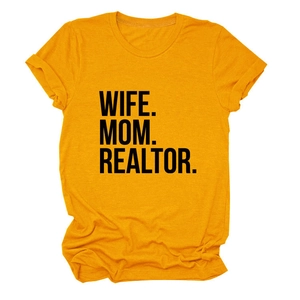 Detailed view of black 'WIFE. MOM. REALTOR.' bold print on mustard yellow cotton t-shirt