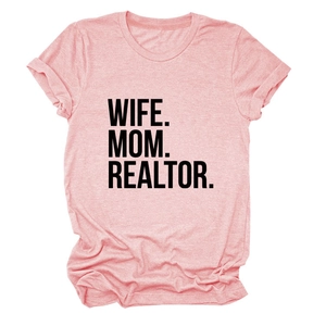 Close-up of pink casual t-shirt showing WIFE MOM REALTOR text print and soft fabric texture