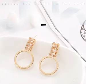 Vue détaillée de boucles d'oreilles rondes dorées avec des pierres de zircon champagne