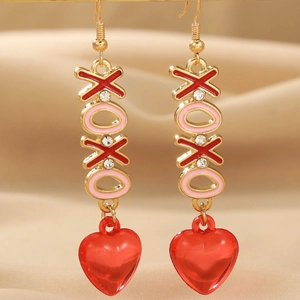Elegant gold XOXO heart drop earrings with red enamel and crystals on silk background