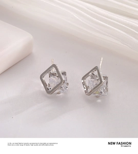 Detail of silver geometric square earrings with sparkling cubic zirconia on silk