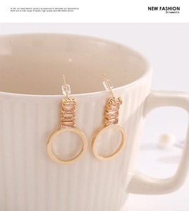 Détail de boucles d'oreilles dorées en zircon champagne sur une tasse en céramique