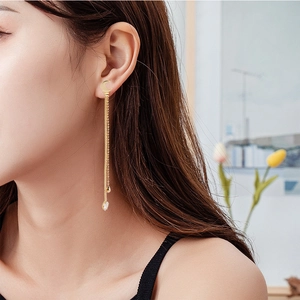 Detail of long gold tassel earrings with crescent moon stud and heart-shaped crystal on model