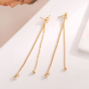 Detail of long gold tassel earrings with box chain and bead chain featuring zircon stone