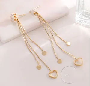 Makroaufnahme von Herz-Quastenohrringen in Gold mit Zirkonia und filigranen Anhängern