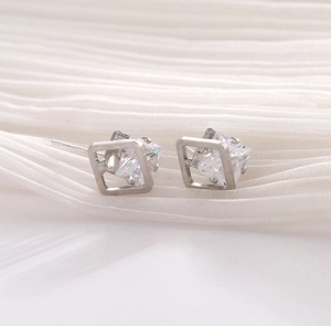 Geometric square stud earrings with central cubic zirconia on elegant white fabric