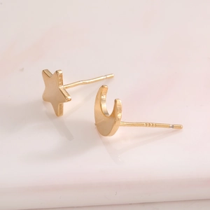 Macro shot of asymmetric star and moon stud earrings in gold finish over S925 silver