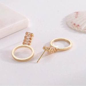 Boucles d'oreilles pendantes dorées avec zircons champagne et cercles sur fond blanc