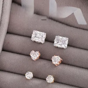 Detailed view of three pairs of sparkling zircon stud earrings in a gray jewelry box