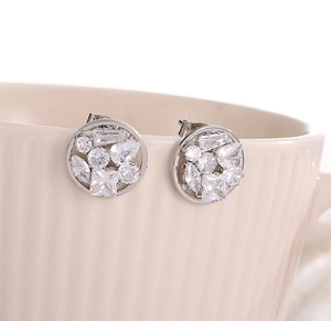 Sparkling S925 silver stud earrings with multi-cut geometric zircons on a ceramic cup