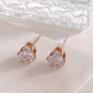 Macro shot of sparkling heart-shaped zircon earrings with rose gold prong setting