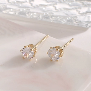 Macro detail of classic gold-plated stud earrings featuring round brilliant cubic zirconia