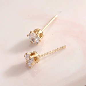 Macro shot of 925 sterling silver gold-plated stud earrings with four-prong cubic zirconia