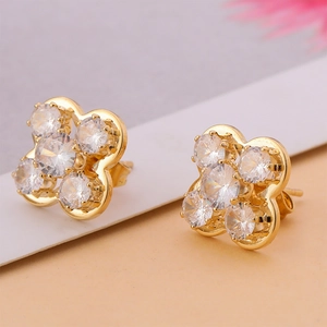 Détail macro de boucles d'oreilles fleur à cinq pétales dorées avec zircons brillants