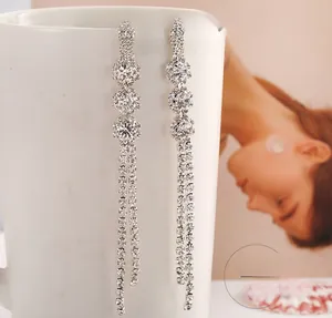 Detailed view of silver snowflake earrings with long rhinestone tassels on a white cup
